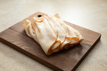 A view of a pile of chipotle chicken breast slices, on a wood board.