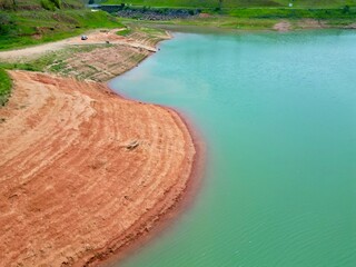 Vista do alto a seca da represa cercada de vegeta&ccedil;&atilde;o e natureza com cores vibrantes.