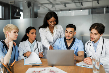 Professional multiethnic team of doctors having video call with patient while COVID-19 pandemic,...