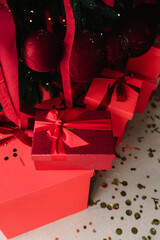 Red Christmas presents under tree with festive lights and ornaments.
