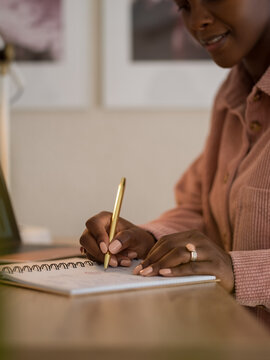 Woman Writing in Notebook While Sitting at Desk in Cozy Workspace