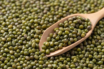 Mung bean in wooden scoop with mung bean seed background, Asian food ingredient