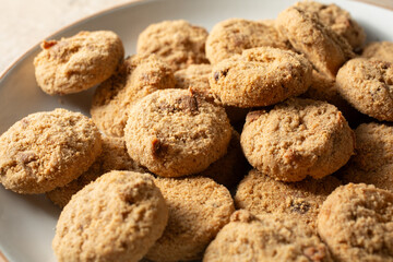 A closeup view of a pile of crunchy chocolate chip cookies, on a plate.