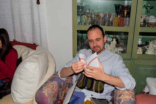 Man Reading a Booklet While Sitting on a Colorful Armchair at Home