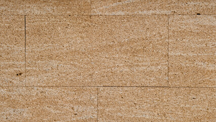 Wall texture background with fossiliferous yellow peach pink orange sandstone slabs cladding. Interior and exterior decoration with rustic mediterranean style textured stone and rock tiles. 