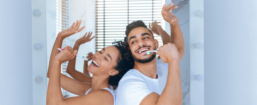 A young couple sings and dances while brushing their teeth in a bright bathroom. They display joy and togetherness, enjoying their morning routine with smiles and laughter.