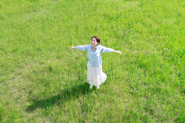 野原で深呼吸をする女性　俯瞰撮影