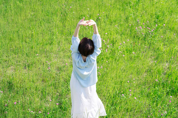 野原で伸びをする女性　俯瞰撮影　後ろ姿