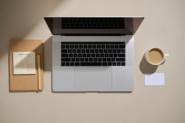 A modern workspace setup featuring a laptop, coffee, and notes