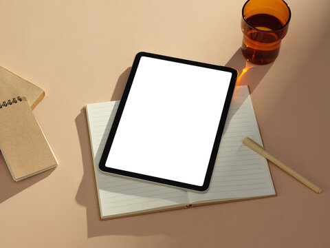 High-angle view of a workspace setup with a tablet, notebook, and pen.