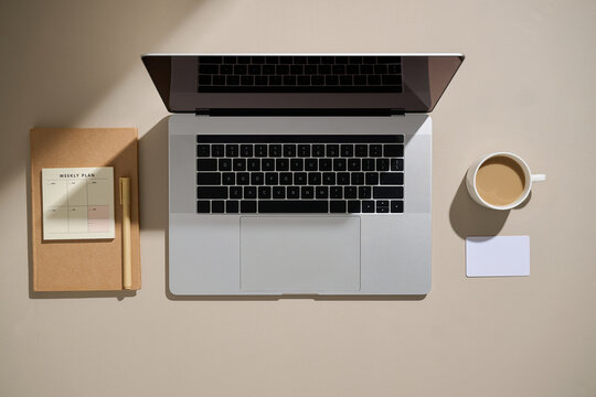 A modern workspace setup featuring a laptop, coffee, and notes