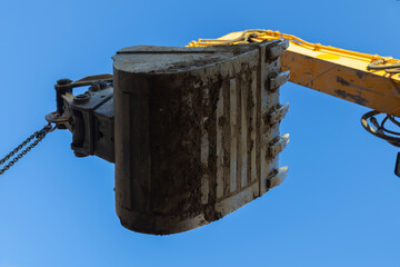 Excavator bucket working against clear blue sky