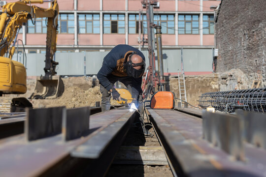 Construction worker welding metal beam at building site