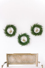 Minimalist Christmas Greenery Wreaths with Gold Bells on White Wall Holiday Decor