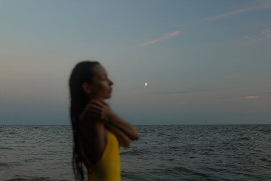 Woman in Yellow Swimsuit Enjoys Serene Sunset by the Ocean