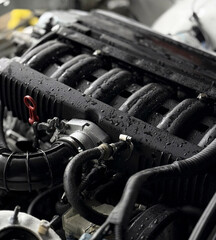Close-up view of a car engine showing droplets on the surface during inspection in a workshop