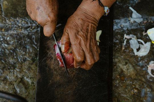 Senior indigenous chef cutting red onion on wooden board