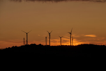 Wind Turbines Silhouetted Against Fiery Sunset Sky