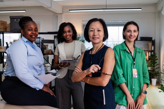 Diverse women smiling in a modern office setting.