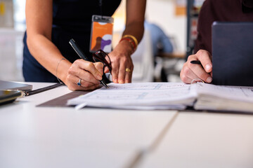 People reviewing documents and making notes at a table.