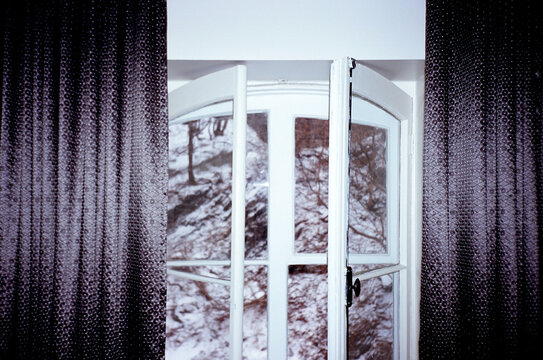 Window and curtains shot with direct flash open to snow covered hill