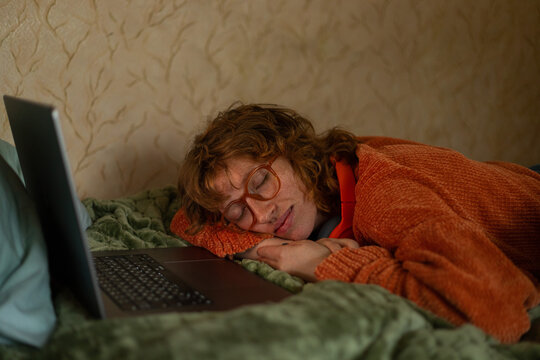 A girl dozes near a laptop