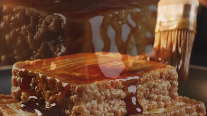 A brush is basting a stack of textured tofu with a glossy brown sauce