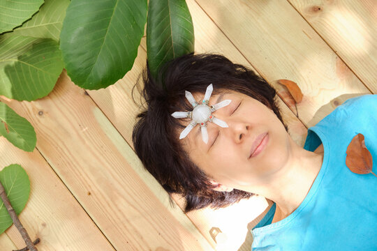 Chinese woman lies on a wooden table with a crystal on her forehead