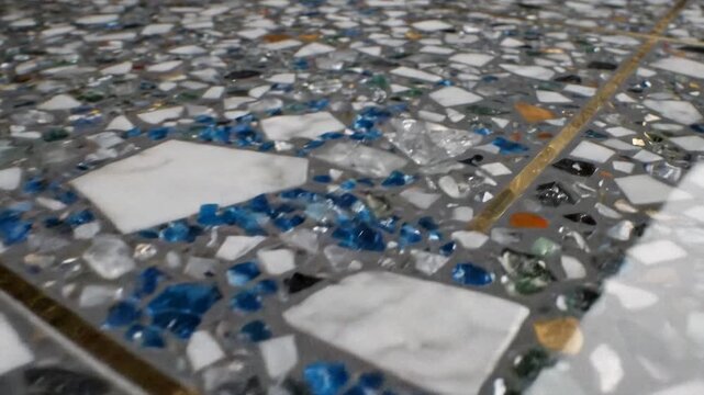 Closeup of a terrazzo surface with embedded glass and marble fragments and brass inlay