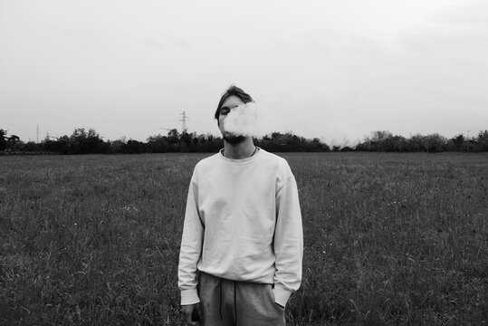 A young man vaping in a field