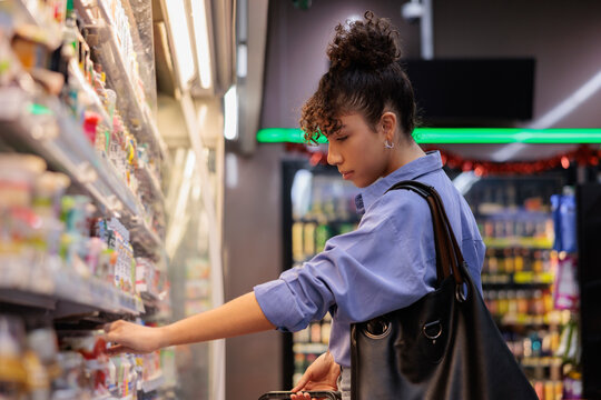 Woman shops for groceries in a supermarket aisle.
