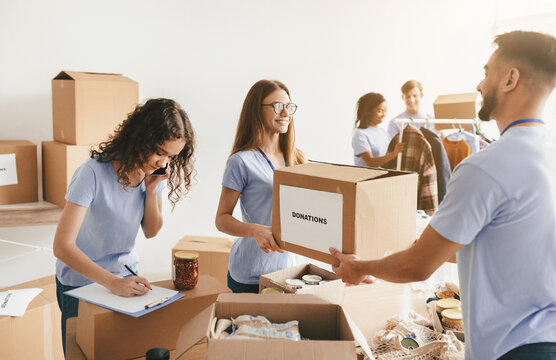 A group of volunteers work together in a bright community center, sorting and organizing donations. - Powered by Adobe