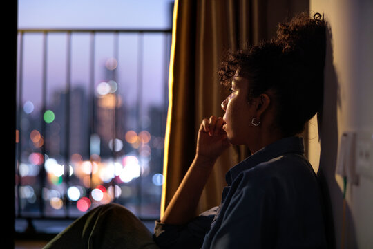 Woman contemplates city lights, lost in thought.