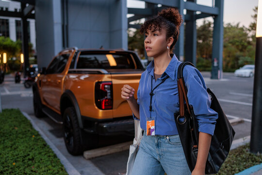 Woman with bag and badge near orange truck.