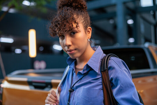 Woman with curly hair and blue shirt near truck.