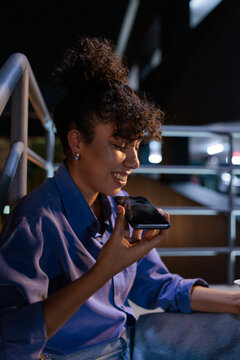 Woman smiles while using voice command on her phone.