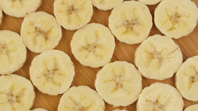 Top view of fresh banana slices pattern rotating on a wooden board. Healthy organic fruit background.