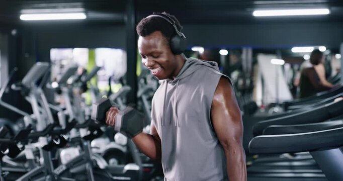 Happy, man and headphones with dumbbell at gym for fitness, streaming podcast and weightlifting. Bodybuilder, equipment and listening to music for bicep training, sports workout and strong muscles