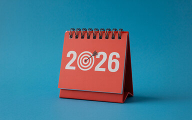 A red desk calendar showing the year two thousand and twenty six with a target symbol on a blue background