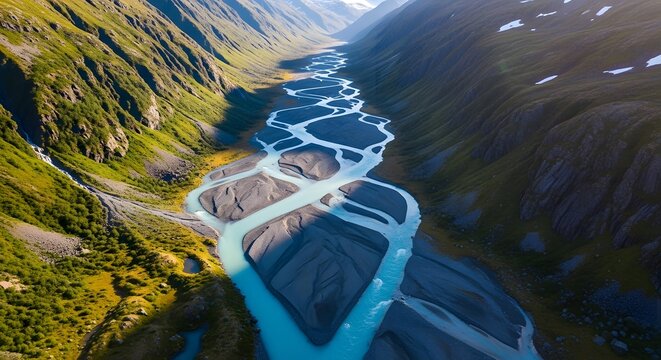 An aerial view of a braided glacial river flowing through a lush green mountain valley.