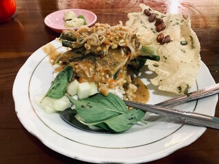 indonesian pecel rice with peanut sauce, vegetables, and rempeyek cracker