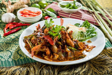 Thai-style seafood stir-fry with shrimp, bell pepper, onion, and spicy red sauce, served with cabbage salad and herbs.