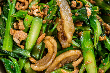 Stir-fried Chinese broccoli with crispy pork belly, seasoned with soy sauce and garlic.
