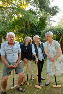 Friends and family enjoy a croquet game in a sunny garden