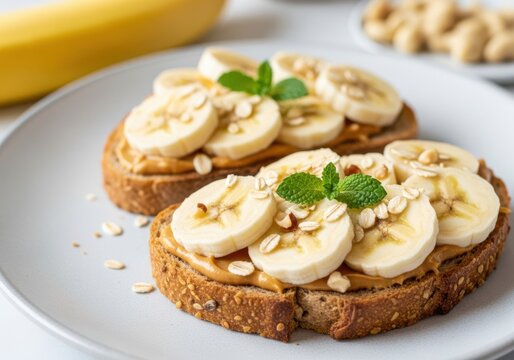 Two slices of whole grain toast topped with peanut butter, fresh banana, and mint leaves on a plate