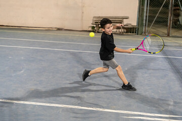 Young Boy Practicing Tennis on an Outdoor Court in the Evening