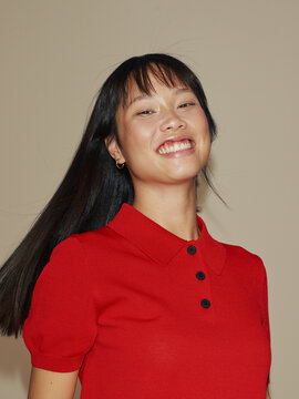 Young Asian Woman Smiling and Wearing a Red Polo Shirt