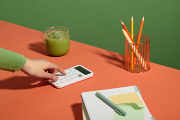 A person calculates numbers with a calculator next to a green drink