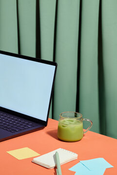 A modern workspace setup with a laptop, matcha, and stationery