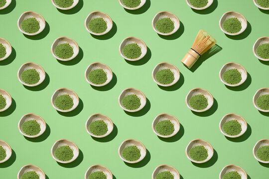 Matcha tea powder displayed in small bowls alongside a whisk